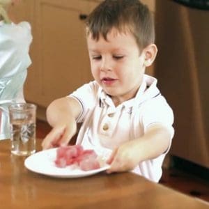 boy picking up plate of food