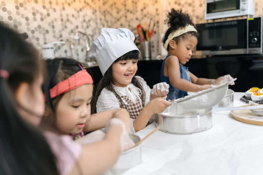 Group of kids are preparing the bakery in the kitchen. Children learning to cooking cookies
