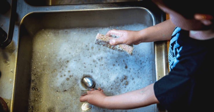 boy washing dishes in sink