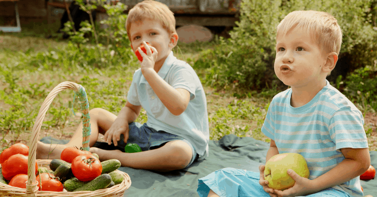Boys outside eating fresh fruits and vegetables