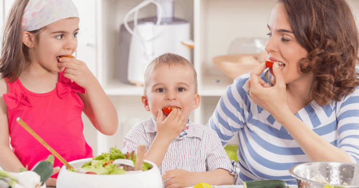 Mom and kids eating tomatoes from a freshly prepared salad.