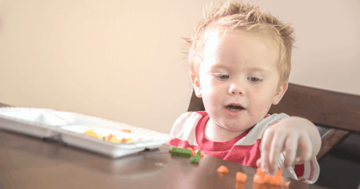 Toddler eating vegetables cut into tiny pieces