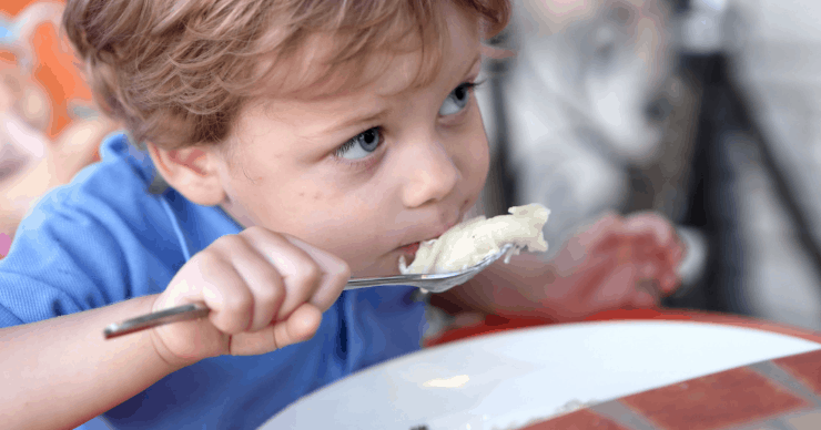 Child eating dinner with a spoon