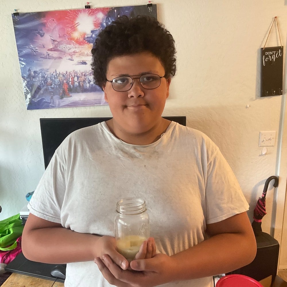 A boy holding the jar of healing salve he made