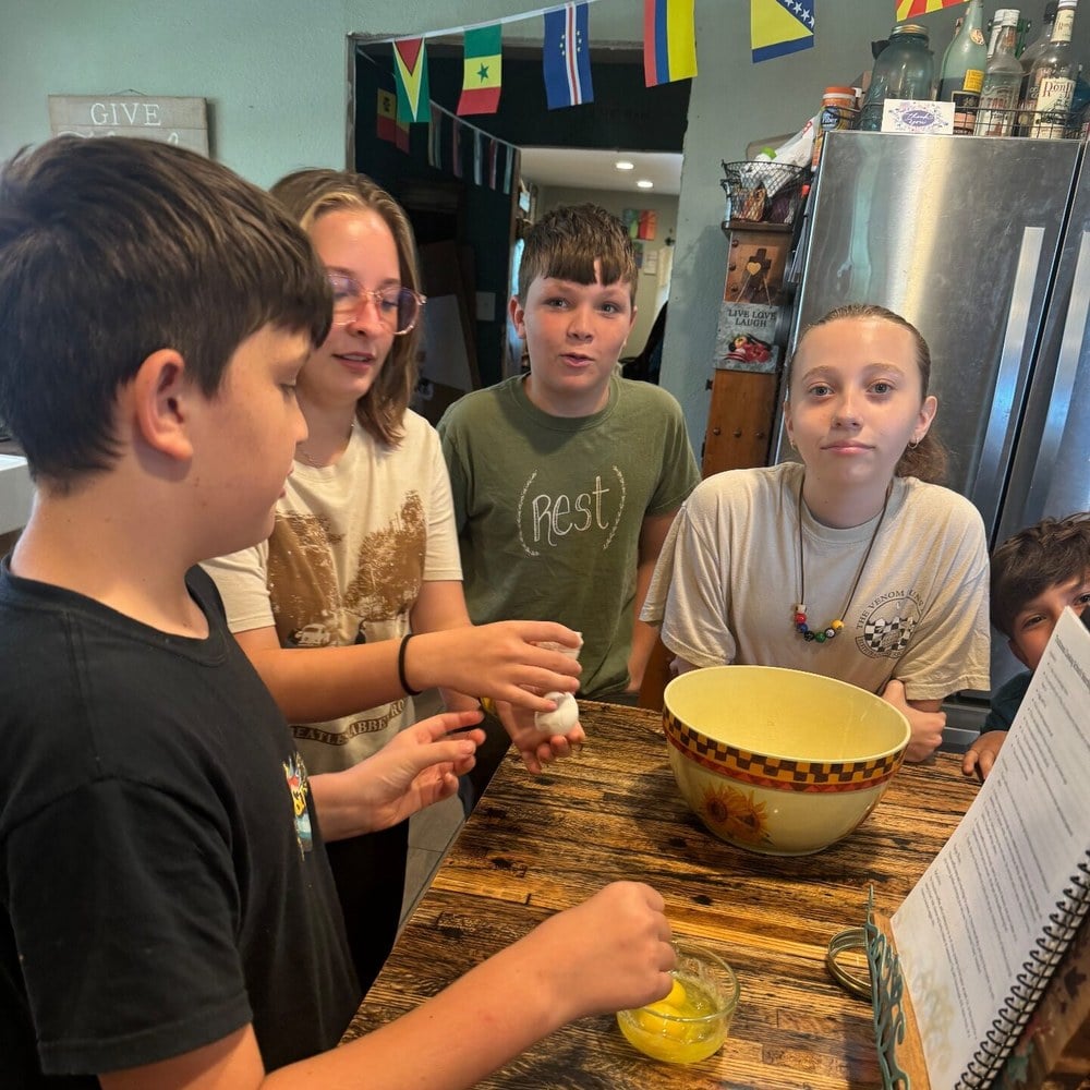 Four children cooking together around the kitchen table