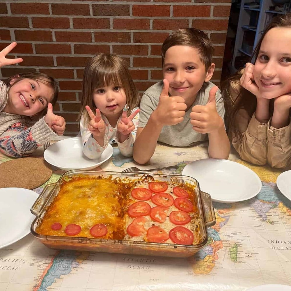 Four children giving a thumbs-up behind the lasagna they made