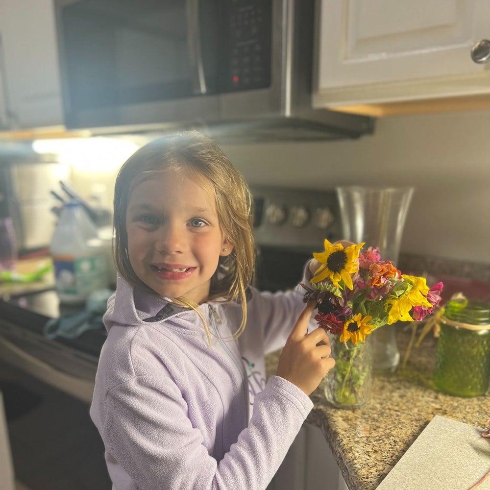 Girl arranging sunflowers in a vase at the kitchen counter