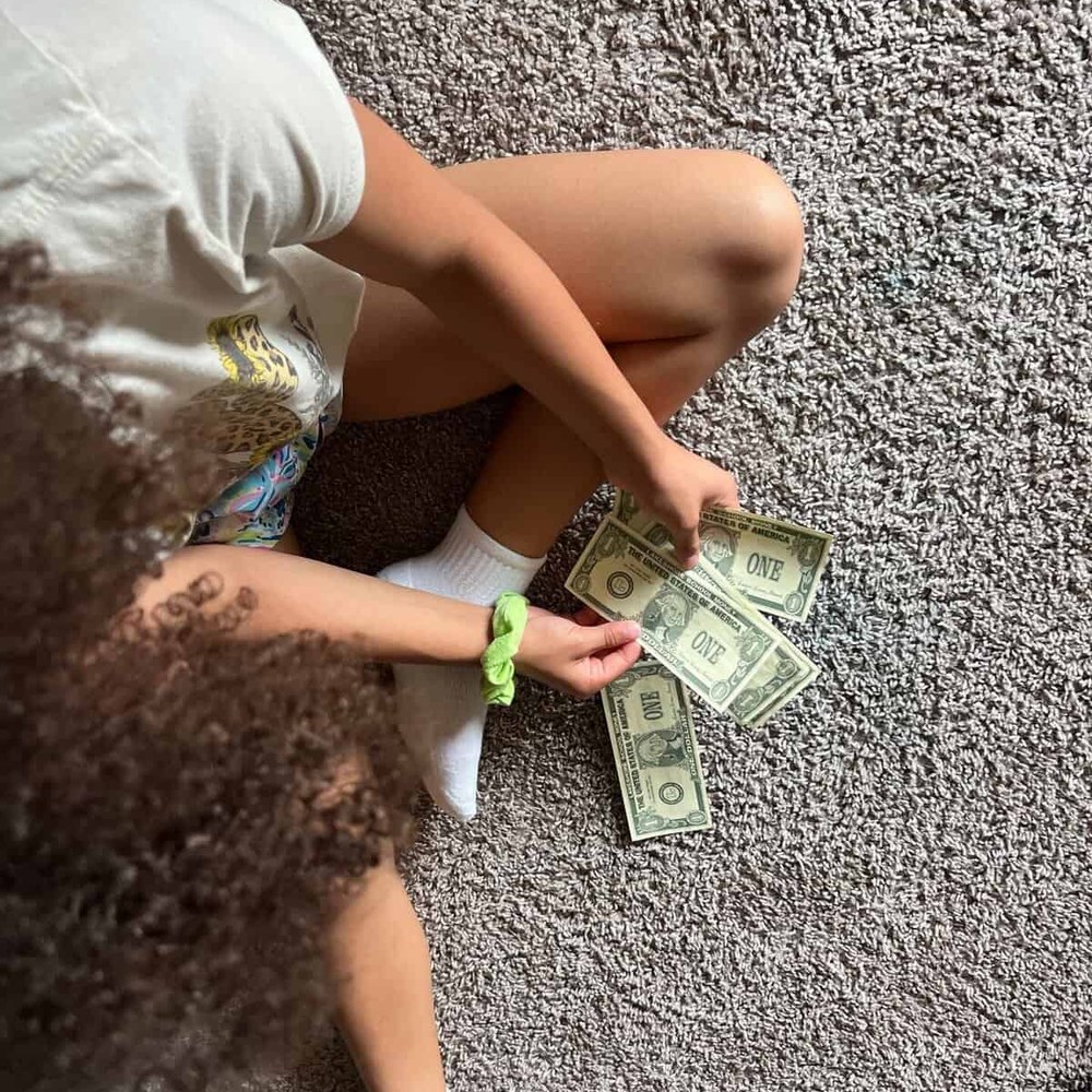 Girl counting out dollar bills on the floor