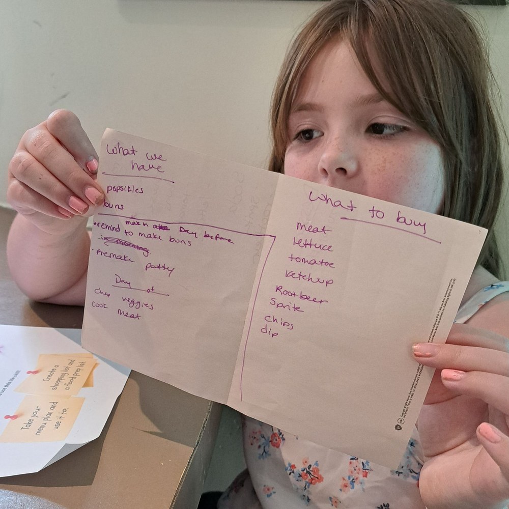 Girl holding up the grocery list she wrote