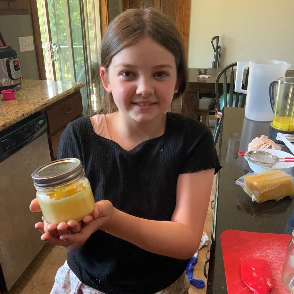 A girl holding the jar of healing salve she made