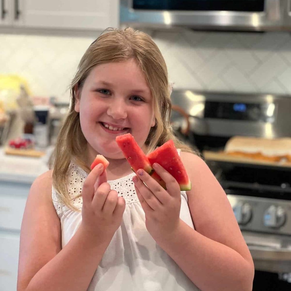 Girl holding up the watermelon sticks she cut