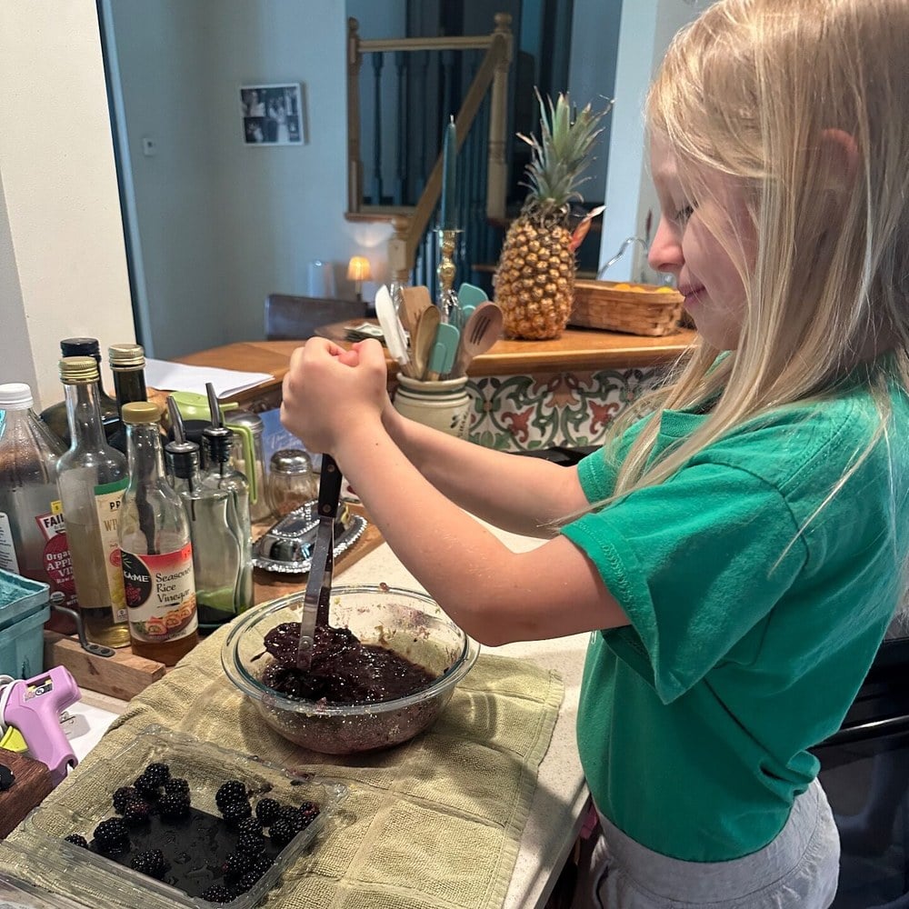 Girl mixing a blackberry, lemon and mint shrub drink