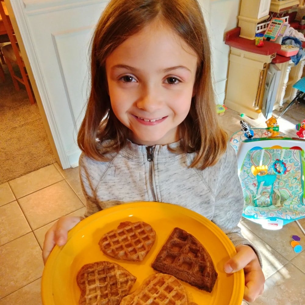 Girl holding a plate of heart-shaped waffles she made