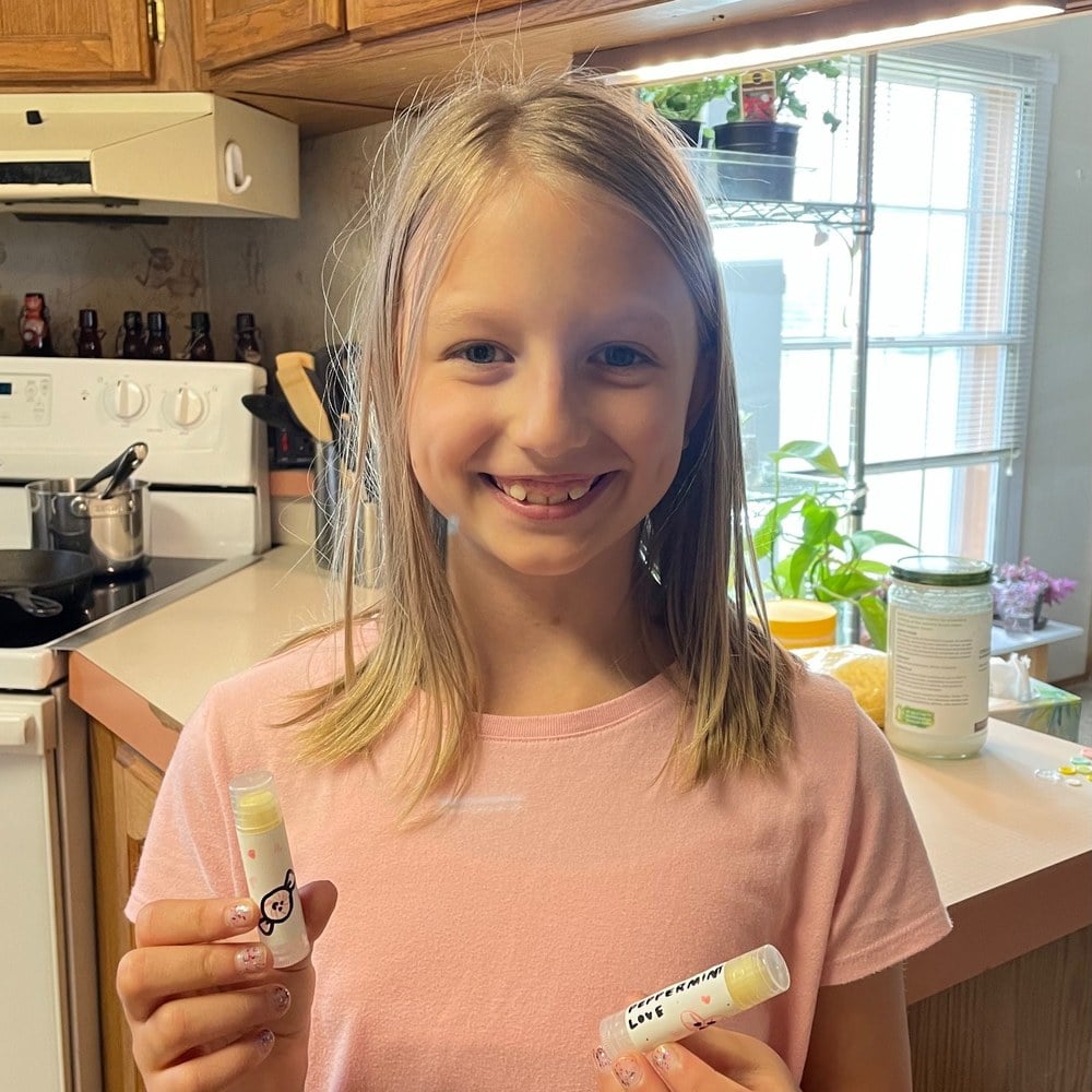 Girl holding up the lip balms she made