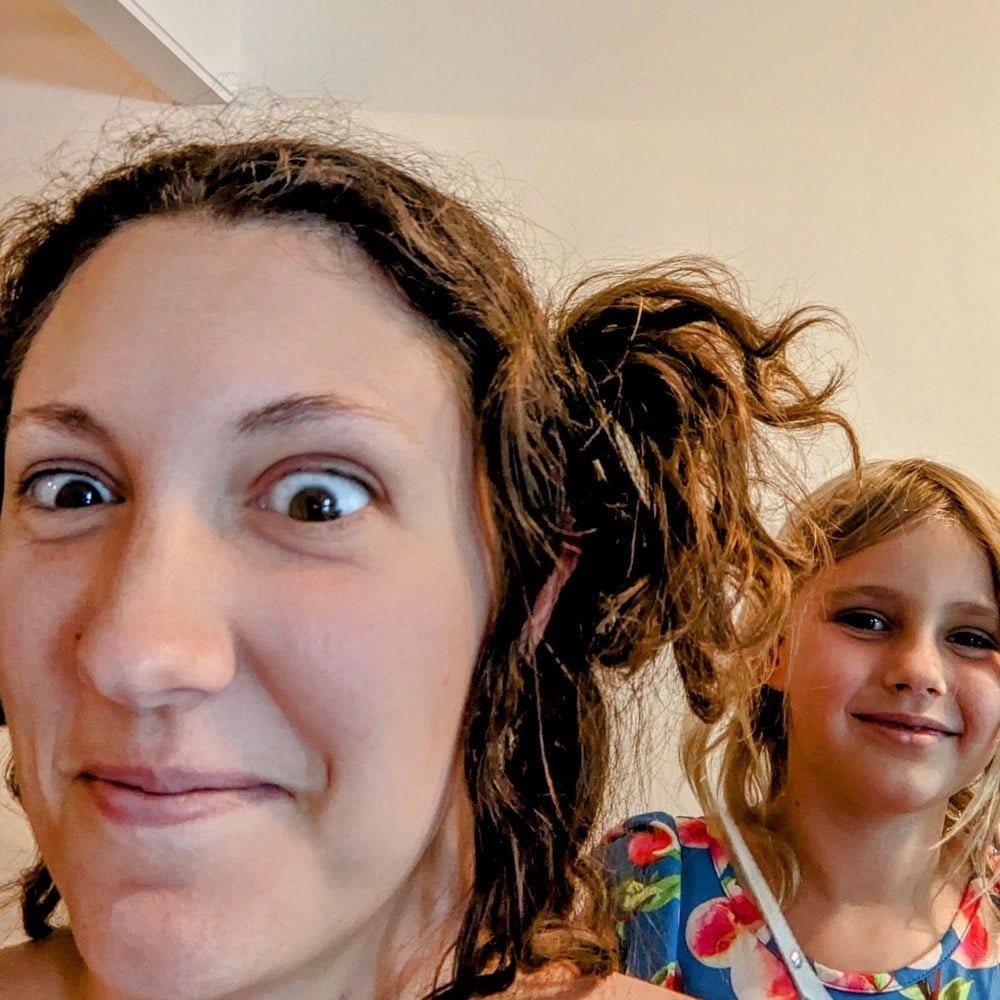A mother and daughter cheek to cheek after a home haircut