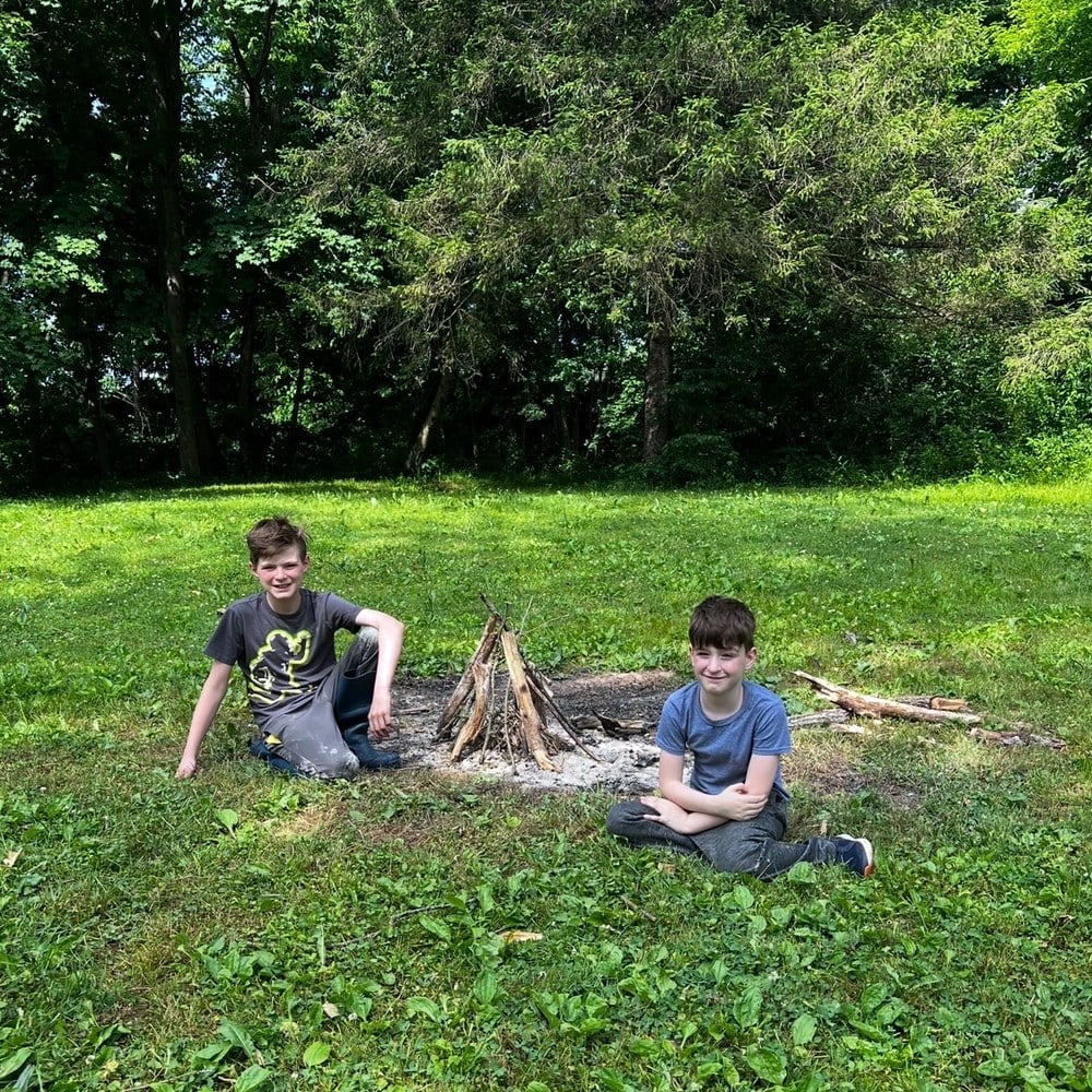 Two boys building a fire ring in the back yard