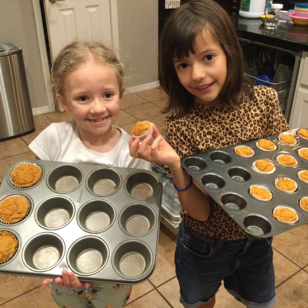 Two girls holding up muffin tins of the snack they baked